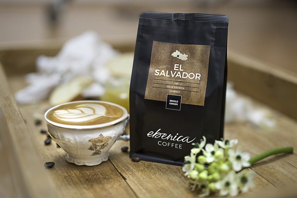 Šálka s cappuccinom a balíčkom kávy El Salvador